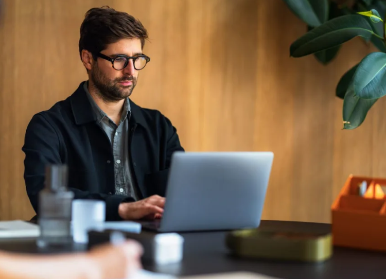 A founder working on a laptop at a wooden desk